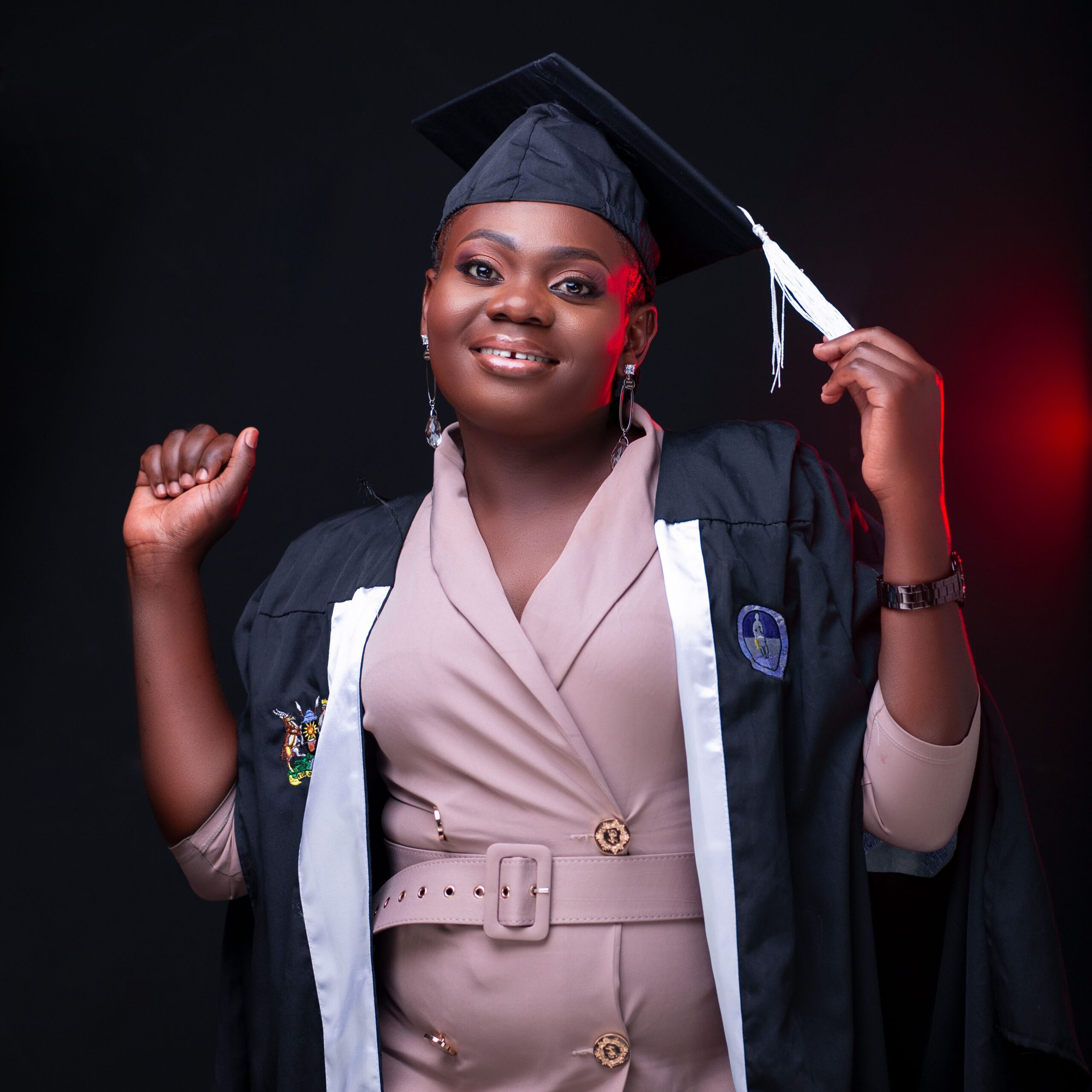 A joyful graduate poses confidently in her cap and gown, celebrating her achievement.